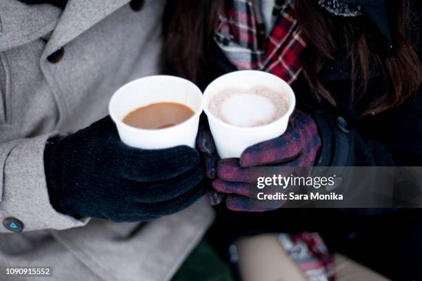 young couple in winter gloves holding takeaway drinks, close up of hands - hot chocolate stock-fotos und bilder
