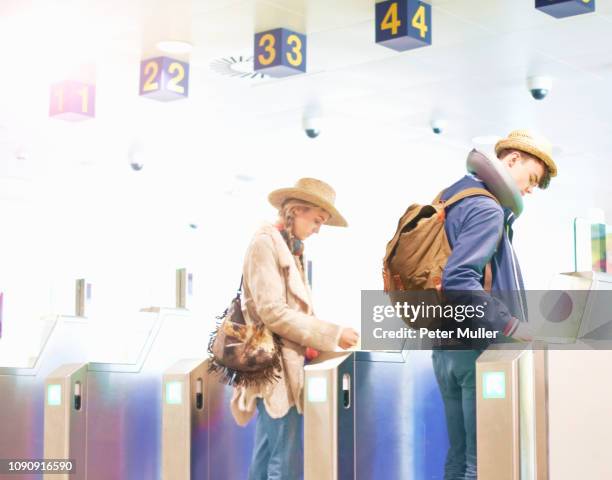 young couple at airport, carrying backpacks, walking through turnstiles - border control stock pictures, royalty-free photos & images