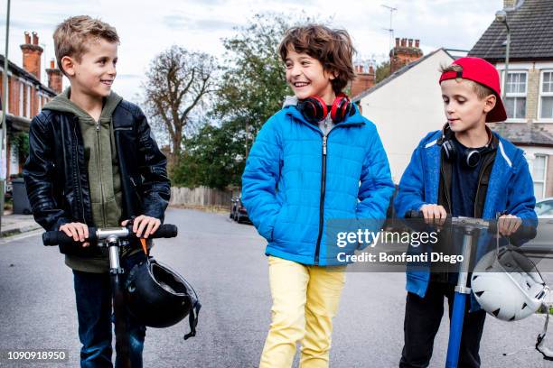 boys riding push scooter on street - center street elementary stock pictures, royalty-free photos & images