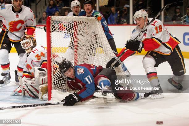 Philippe Dupuis of the Colorado Avalanche is checked into the back of the goal by Matt Stajan of the Calgary Flames as goalie Mikka Kiprusoff of the...