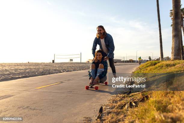 gelukkige paar schaatsen in venice beach - californië - venice couple stockfoto's en -beelden