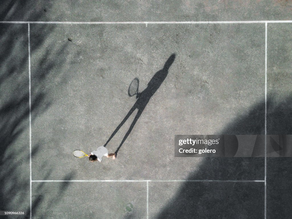 Drone vistas tenis courd duro con chica en sol de la tarde