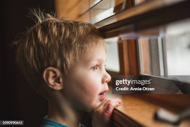 boy looking out a window - boy looking out window stock pictures, royalty-free photos & images