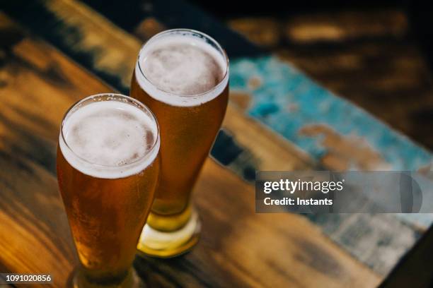 um tiro lá fora, à noite, close-up de duas cervejas geladas num terraço de um café-bar calçada fort de france. - microcervejaria - fotografias e filmes do acervo