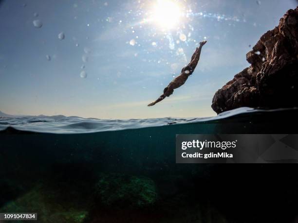 man jumping into water from rocks wild - half full stock pictures, royalty-free photos & images