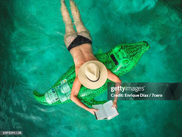 woman in pool reading - women sunbathing pool stock pictures, royalty-free photos & images