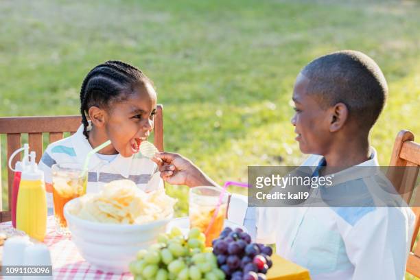 boy giving potato chip to little brother - family eating potato chips stock pictures, royalty-free photos & images