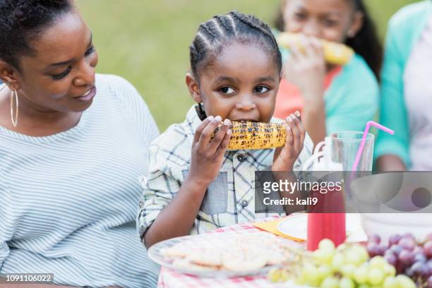 piccolo ragazzo afro-americano in grembo alla madre al cookout - bbq corn foto e immagini stock