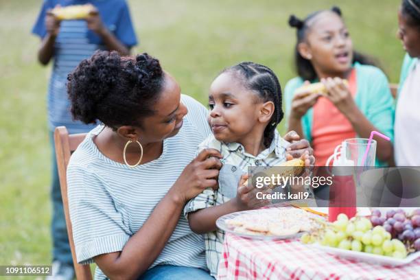 piccolo ragazzo afro-americano in grembo alla madre al cookout - bbq corn foto e immagini stock