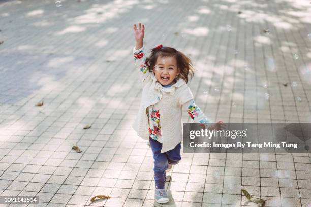 toddler girl chasing soap bubbles joyfully under the sun. - running in the sun stock-fotos und bilder