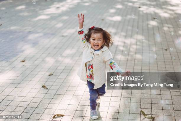 toddler girl chasing soap bubbles joyfully under the sun. - cute little asian girls 個照片及圖片檔