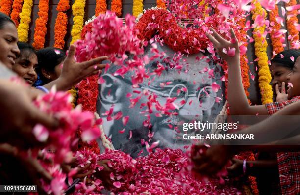 Indian students throws rose flower petals over a portrait of Mahatma Gandhi during a gathering to pay tribute on the 71st death anniversary of the...