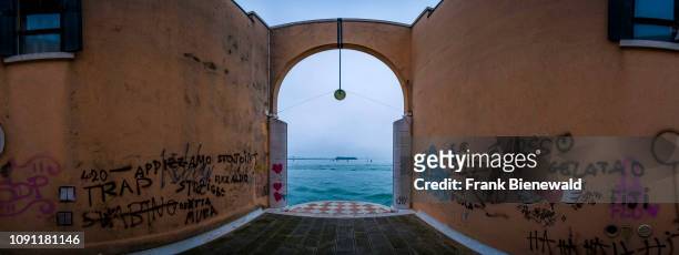 Panoramic view of a gate, sprayed with colorful graffity, leading out to the waters of the Venetian Lagoon, Laguna di Venezia.