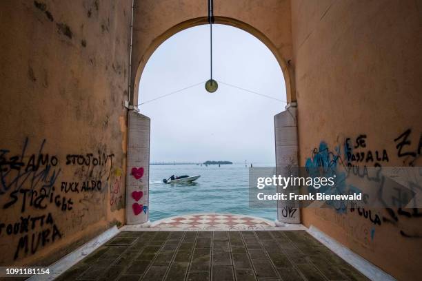 Gate, sprayed with colorful graffity, is leading out to the waters of the Venetian Lagoon, Laguna di Venezia.