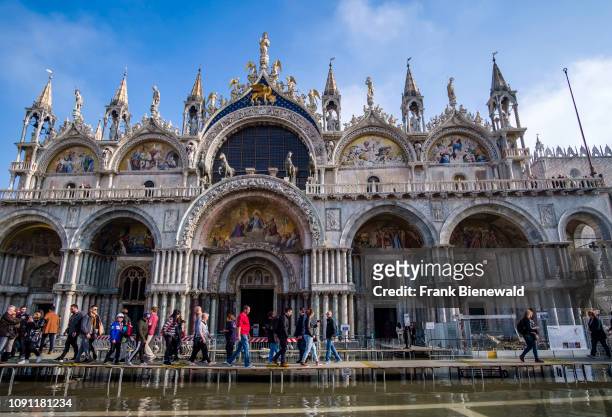 Many tourists are walking on footbridges in front of Saint Mark's Basilica, Basilica di San Marco, San Marco Square, Piazza San Marco flooded during...