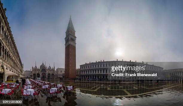 Panoramic view on San Marco Square, Piazza San Marco, with empty tables and chairs of a restaurant, flooded during the Acqua alta.