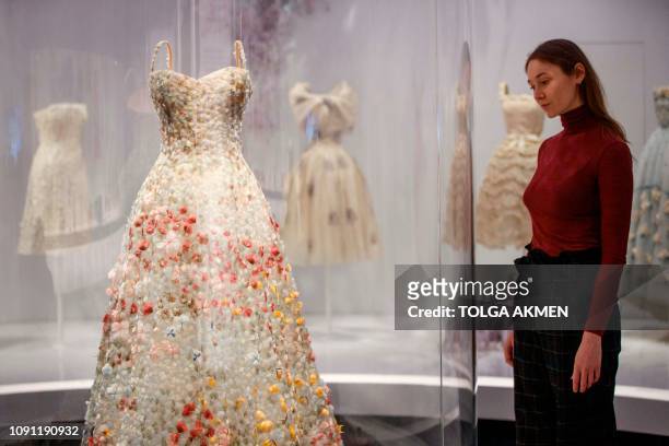 Assistants pose by a Jardin Fleuri bustier dress by Maria Grazia Chiuri on show at 'Christian Dior: Designer of Dreams' exhibition at the Victoria...