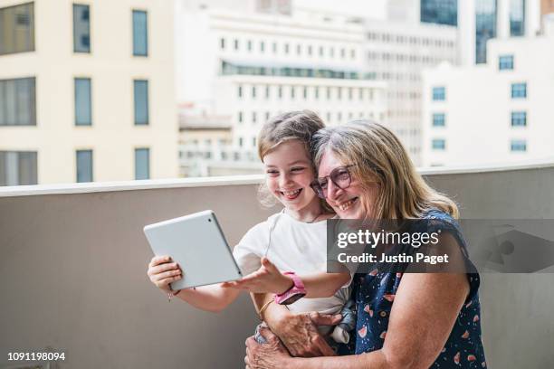 senior lady and granddaughter taking selfie on tablet - street style australia stock pictures, royalty-free photos & images