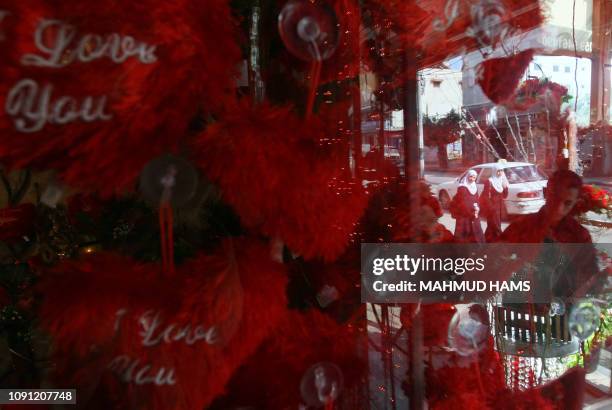 Two Palestinian school girls walk past as a vendor prepares a window shop on Valentine's Day in Gaza City on February 14, 2011. AFP PHOTO/MAHMUD HAMS