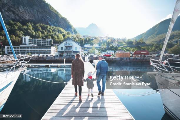 family walking on pier at sunny day - dreiviertel rückansicht stock-fotos und bilder