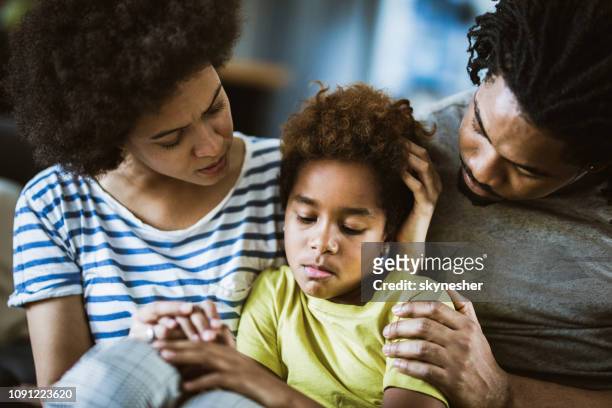 african american parents consoling their sad girl at home. - distraught family stock pictures, royalty-free photos & images