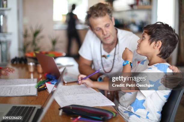 a family of four doing homework together at home. - step father stock pictures, royalty-free photos & images