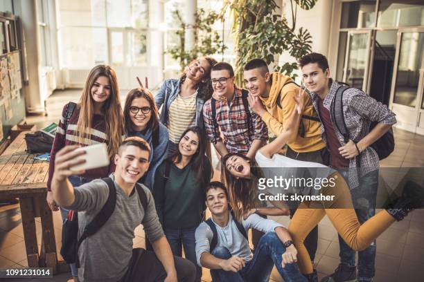 large group of happy students taking a selfie with cell phone at school. - boy girl stock pictures, royalty-free photos & images