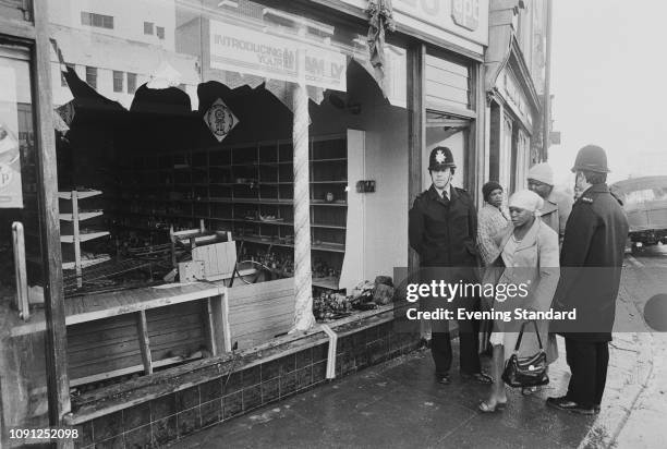 Two police officers and three woman standing outside a damaged shop following the St Pauls Riot in Bristol, UK, 3rd April 1980.