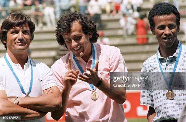 French midfielder Michel Platini jokes as coach Henri Michel and midfielder Jean Tigana stand on the podium after receiving the bronze medal...