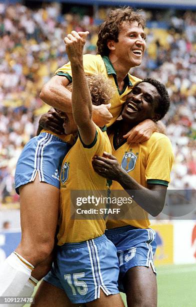 Brazilian midfielder Zico jumps on teammates Alemao and Josimar after Brazil scored a goal against Northern Ireland 12 June 1986 in Guadalaraja...