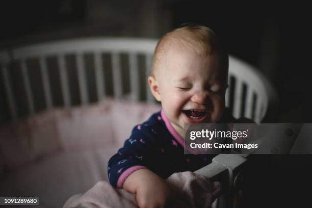 high angle close-up of cute happy baby girl standing in crib at home - dark baby stock pictures, royalty-free photos & images