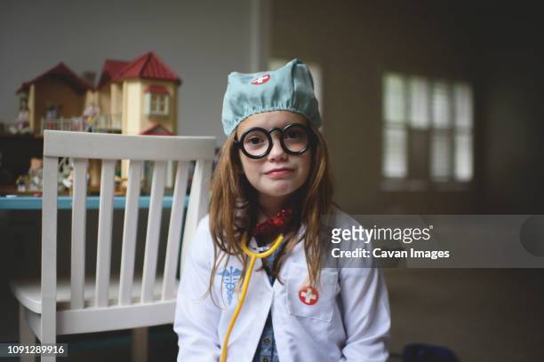 portrait of cute girl in doctor's costume sitting at home - child playing dress up stock-fotos und bilder