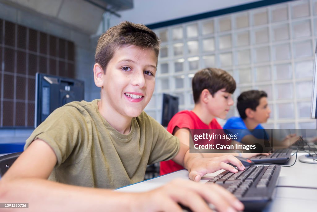 Schoolboy Using Computer Portrait Of Schoolboy Using Desktop Computers With Friends In Classroom ...
