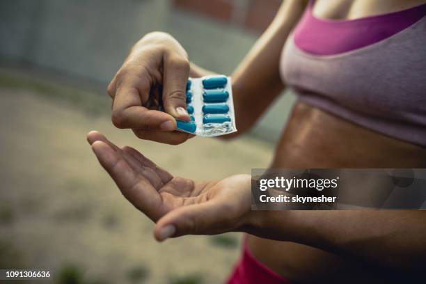 close up van onherkenbaar atletische vrouw nemen van supplementen. - exercise pill stockfoto's en -beelden