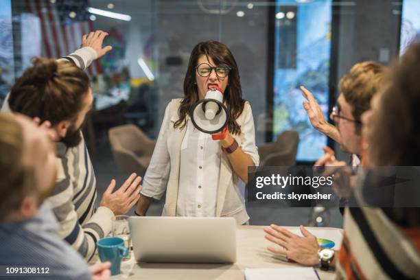 rude female leader yelling at her coworkers through megaphone in the office. - work conflict stock pictures, royalty-free photos & images