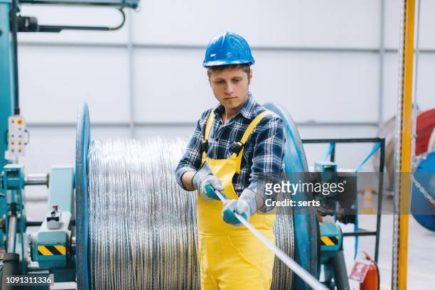 porträtt av ung affärsman arbetar med kabel rulle i fabrik - cable bildbanksfoton och bilder