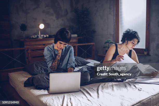 lesbian couple paying bills in bed - lady personal loan stock pictures, royalty-free photos & images