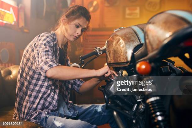 garaje de motos con estilo vintage hobby. mujer en el trabajo - vintage motorcycle fotografías e imágenes de stock