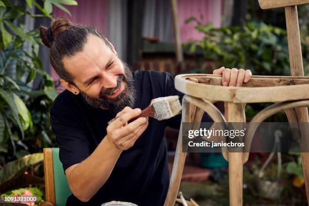 fai-da-te in giardino. uomo che dipinge sedia di legno - garden furniture foto e immagini stock