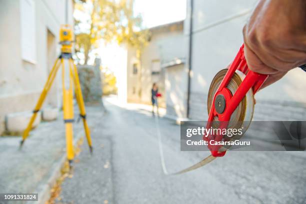 landmeters met meten tape op straat - cartograaf stockfoto's en -beelden