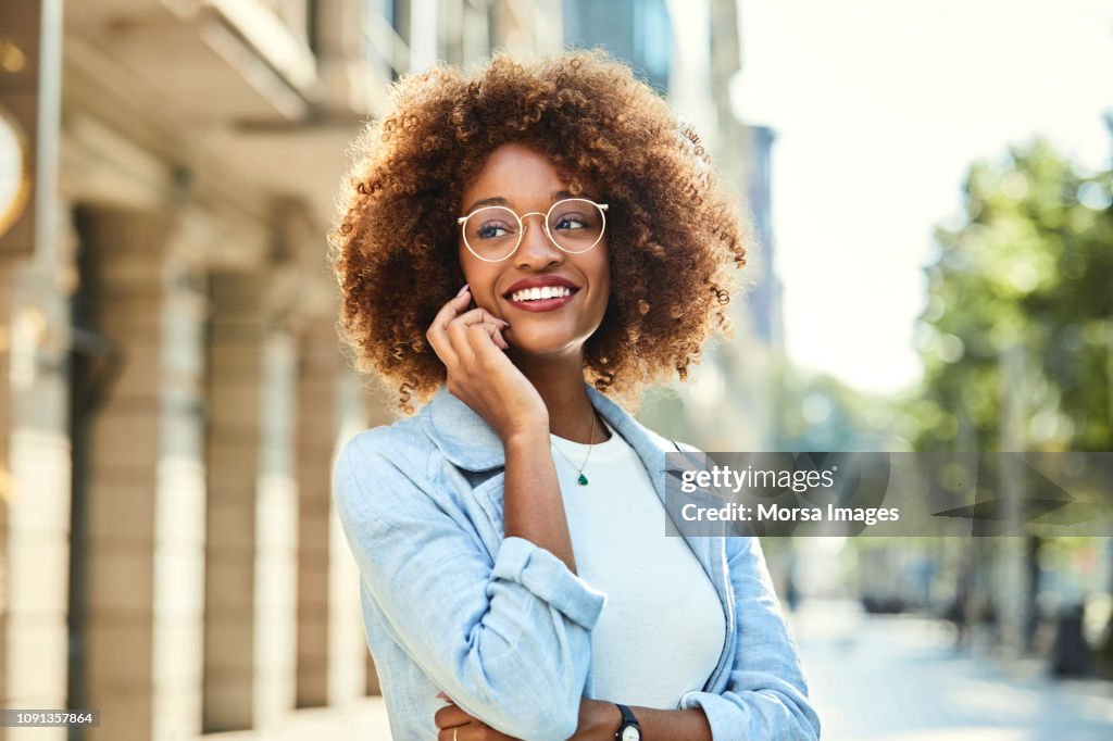 Woman using smart phone at sidewalk in city