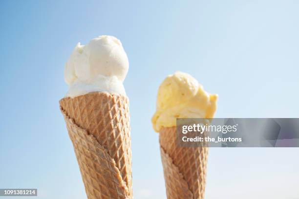 close-up of two ice cream cones against blue sky - holding two things stock pictures, royalty-free photos & images