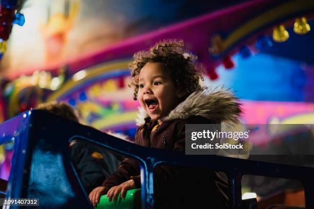 jong meisje op een carrousel - draaimolen stockfoto's en -beelden