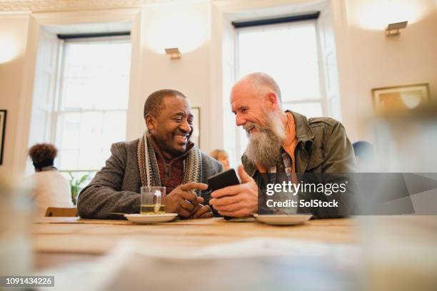 catching up in a cafe - senior men talking stock pictures, royalty-free photos & images