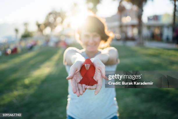 young woman with red aids awareness ribbon - world aids day stock pictures, royalty-free photos & images