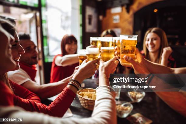 people talking and toasting in a pub with the beers - bebedeira imagens e fotografias de stock