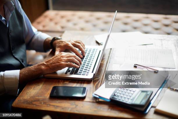 senior businessman typing on a laptop in a coworking space - independence imagens e fotografias de stock