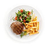 Grilled beefsteak, french fries and vegetables on white background
