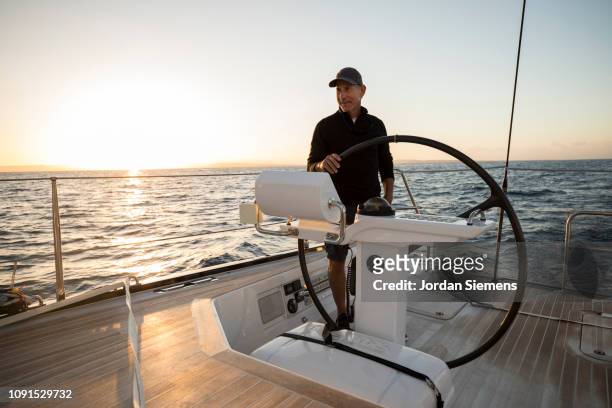 a man sailing a beautiful yacht on the open ocean. - rich sailing imagens e fotografias de stock