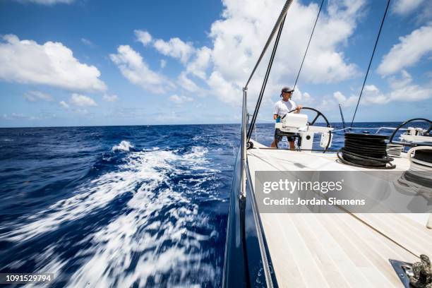 a man sailing a beautiful yacht on the open ocean. - navegación en yate fotografías e imágenes de stock